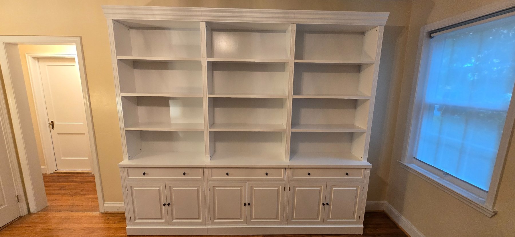 Large white multi-section shelving and cabinet storage wall assembled in a home